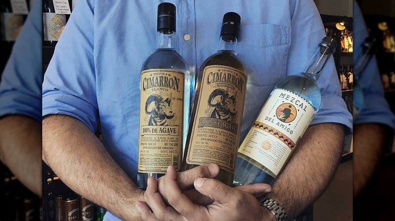 person holding three tequila bottles