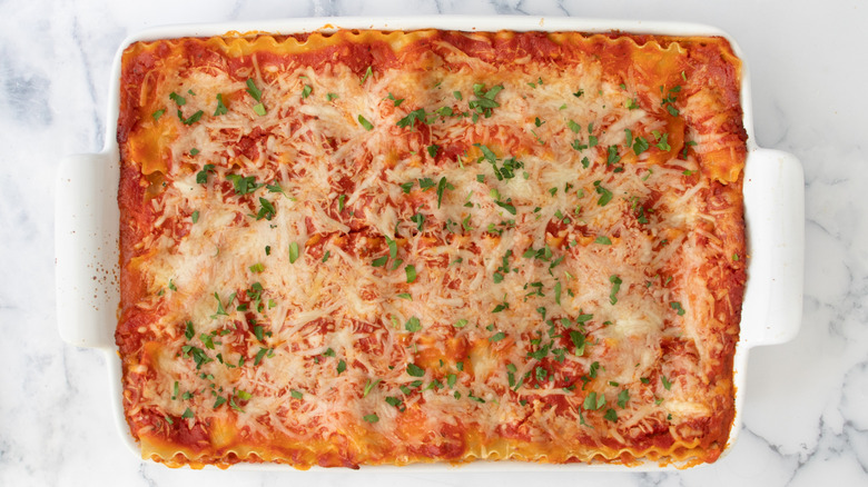 herb-topped lasagna in a white baking pan