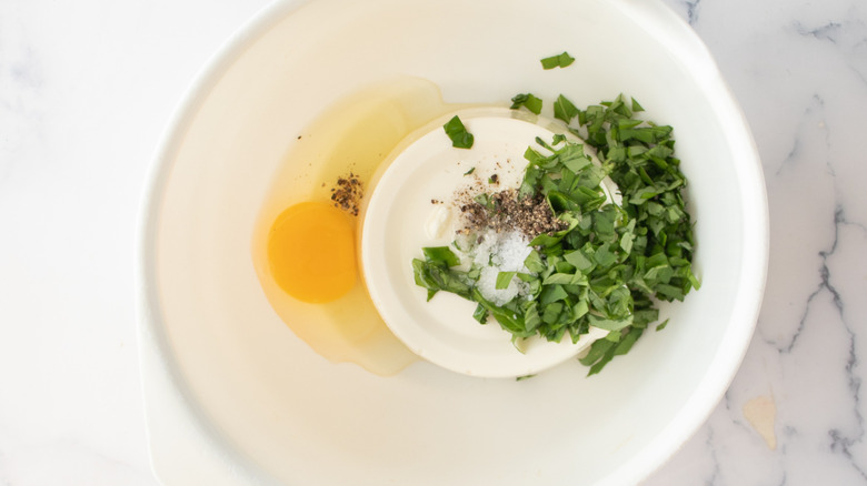 ricotta cheese, egg, and basil in a white bowl