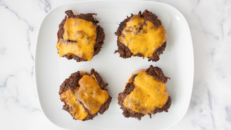 bun halves topped with burger patties and melted cheese on plate
