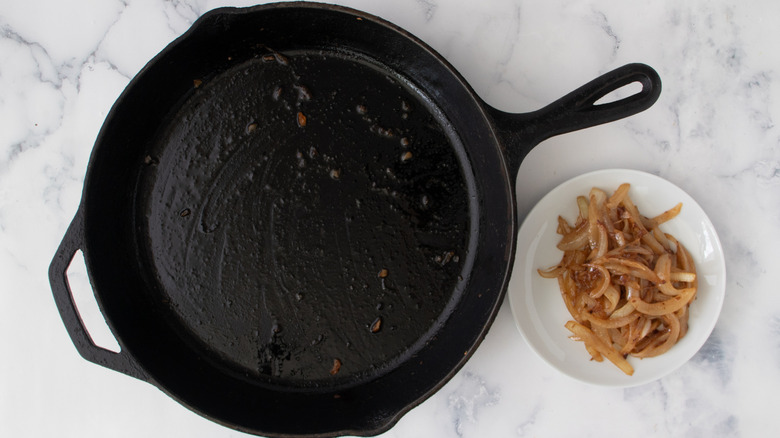 cooked onions and garlic in bowl next to skillet