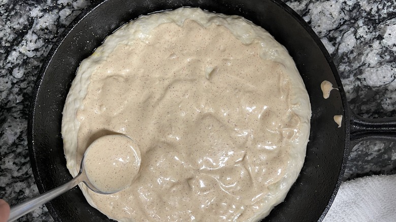spreading chipotle lime mayo on pizza dough in skillet