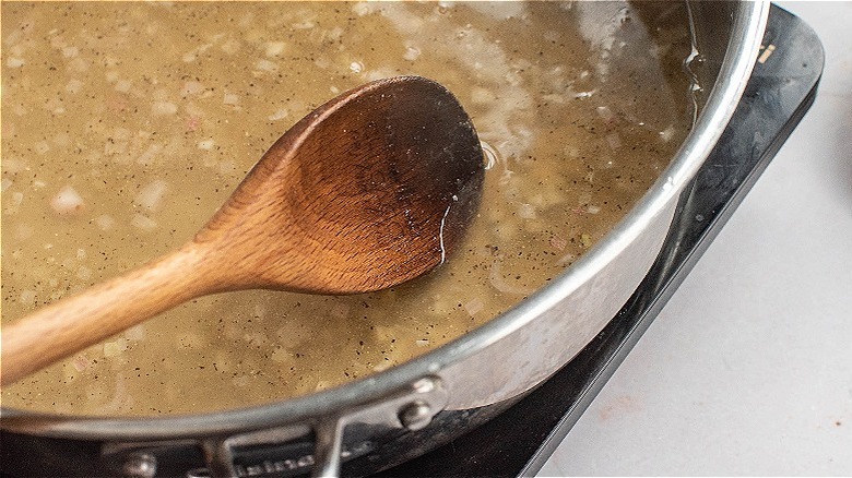 spoon stirring broth in skillet