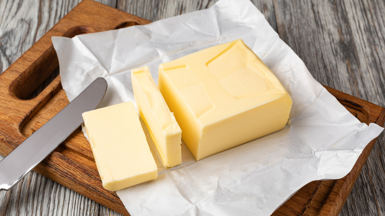 Sliced block of butter on wrapper with butter knife