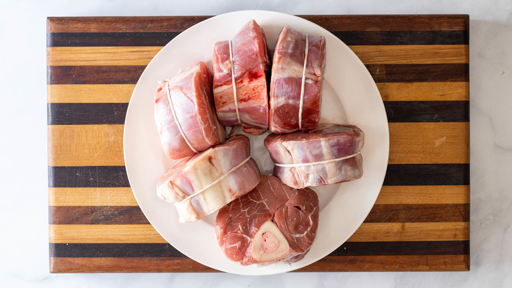 veal shanks on white plate on wooden cutting board ossobuco