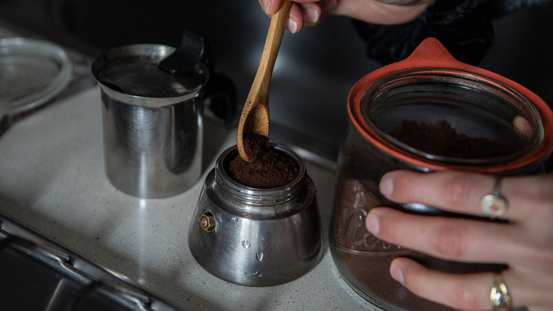 spooning coffee grounds into percolator