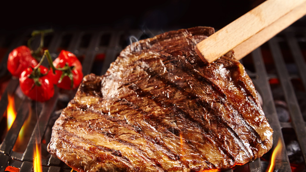 turning over seared steak on a grill 